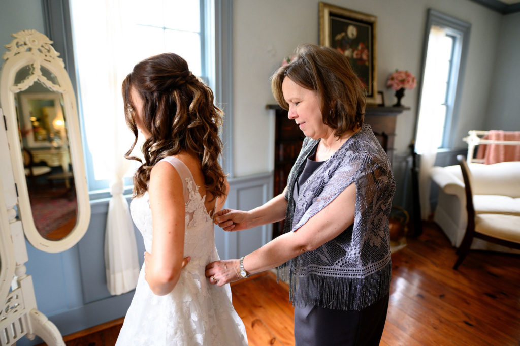 mother of the bride zipping brides dress up
