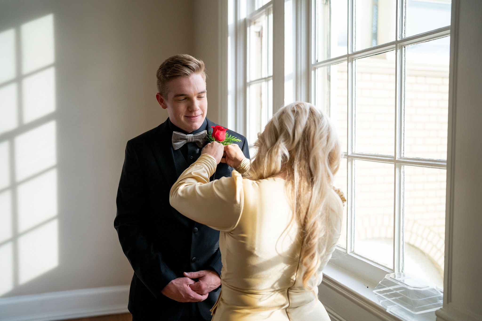 mother of the groom pinning a rose to her son
