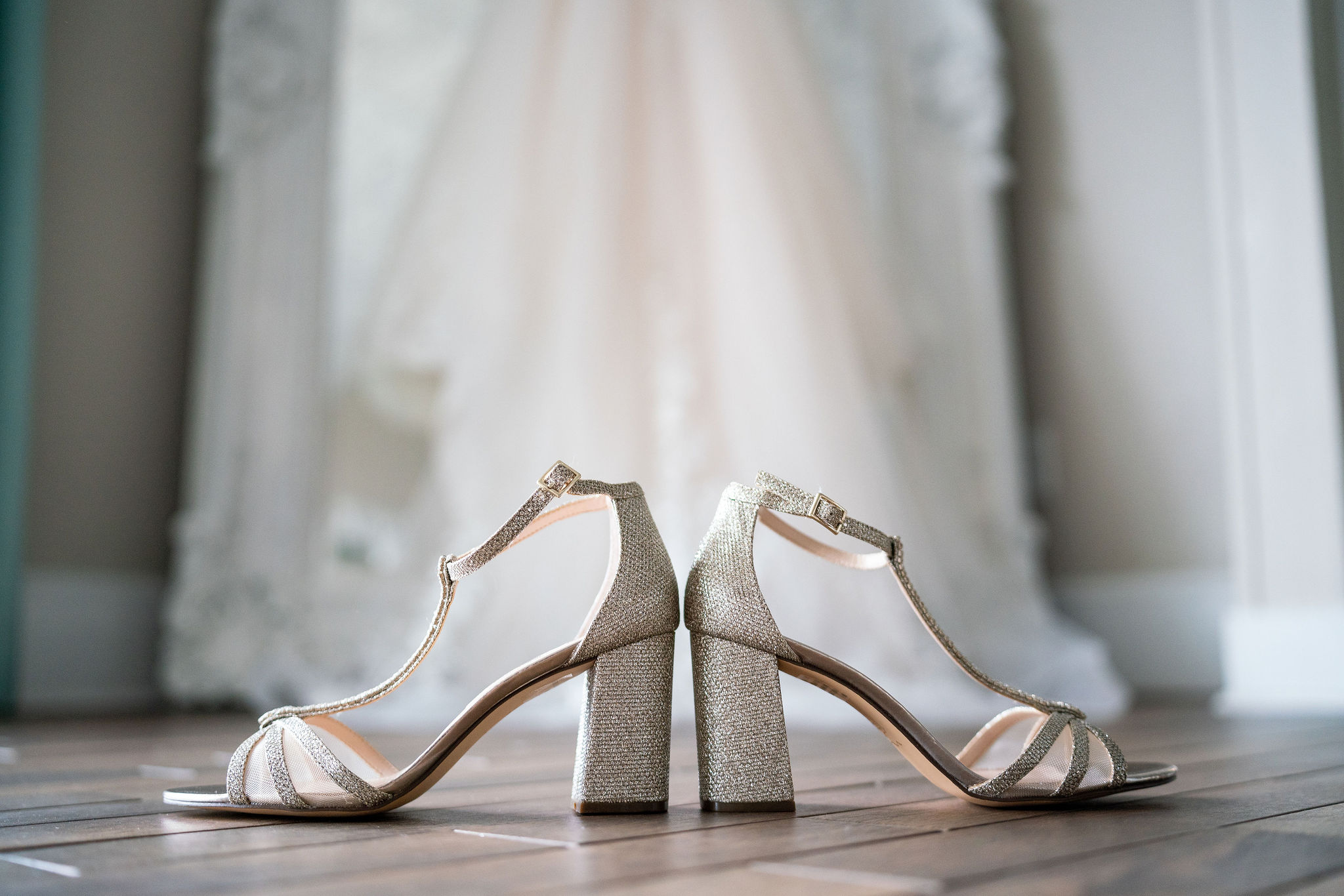 wedding shoes in front of a hanging dress